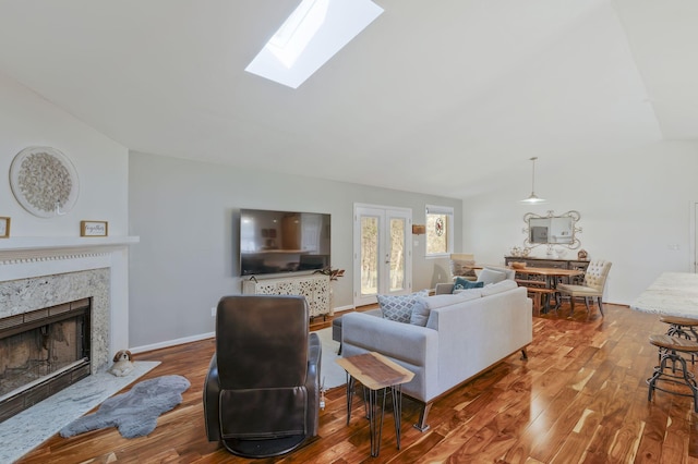 living room featuring hardwood / wood-style flooring, a skylight, and a premium fireplace