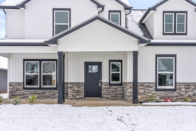 snow covered property entrance with covered porch