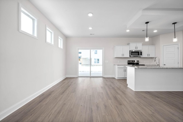 kitchen featuring appliances with stainless steel finishes, white cabinets, hanging light fixtures, light hardwood / wood-style floors, and light stone countertops