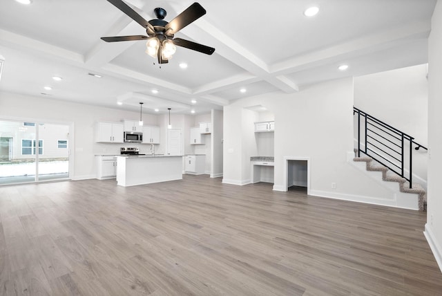 unfurnished living room with beamed ceiling, ceiling fan, and dark hardwood / wood-style flooring