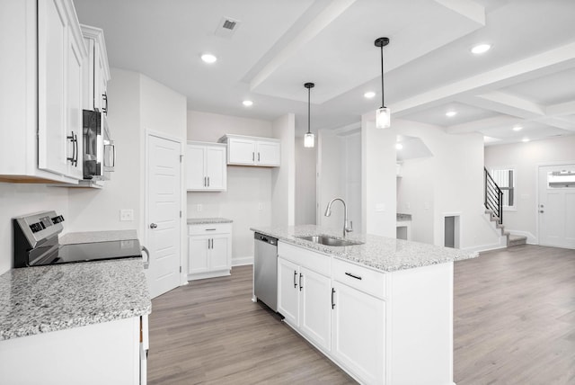 kitchen featuring white cabinetry, light stone counters, decorative light fixtures, a center island with sink, and appliances with stainless steel finishes