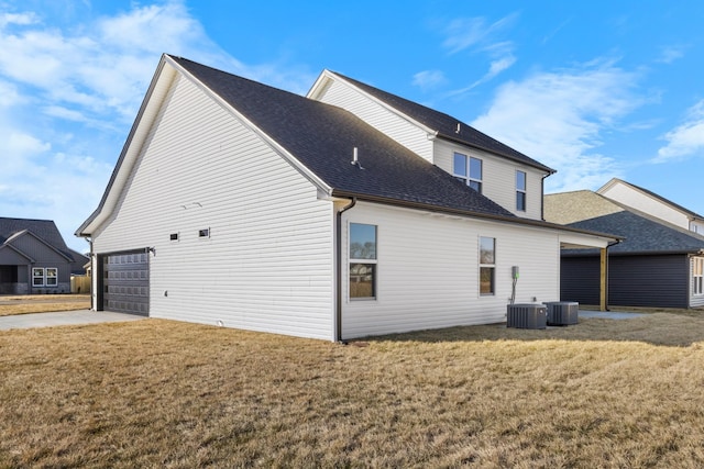 rear view of property with central AC unit, a garage, and a lawn