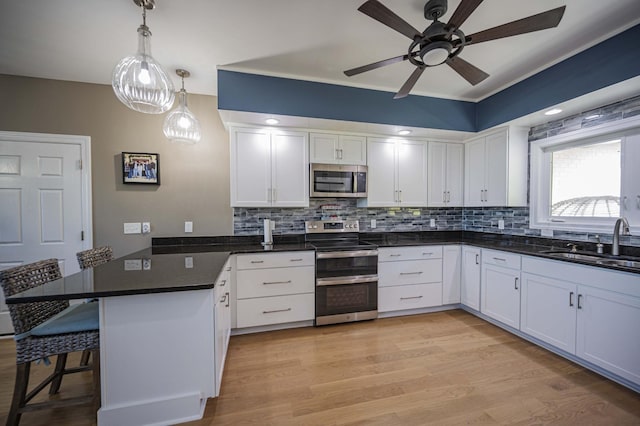 kitchen with white cabinets, a kitchen breakfast bar, stainless steel appliances, and sink