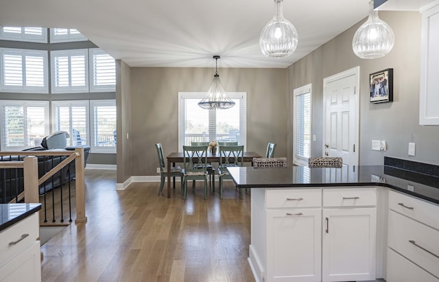 kitchen with dark hardwood / wood-style flooring, an inviting chandelier, white cabinetry, and hanging light fixtures