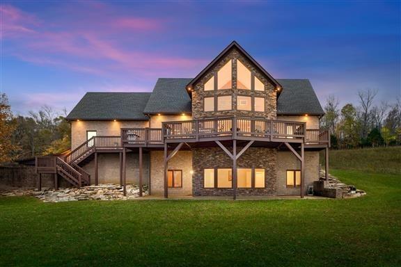 back house at dusk with a yard and a wooden deck