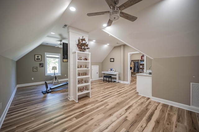 workout area with light hardwood / wood-style flooring, ceiling fan, and lofted ceiling