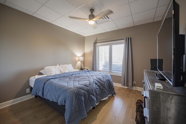 bedroom with wood-type flooring, a paneled ceiling, and ceiling fan