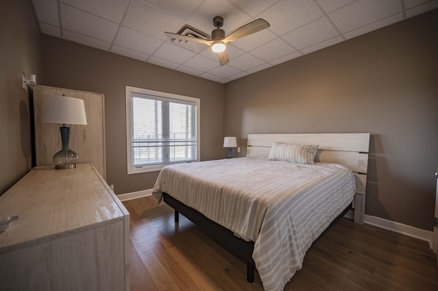 bedroom with ceiling fan, a drop ceiling, and dark hardwood / wood-style floors