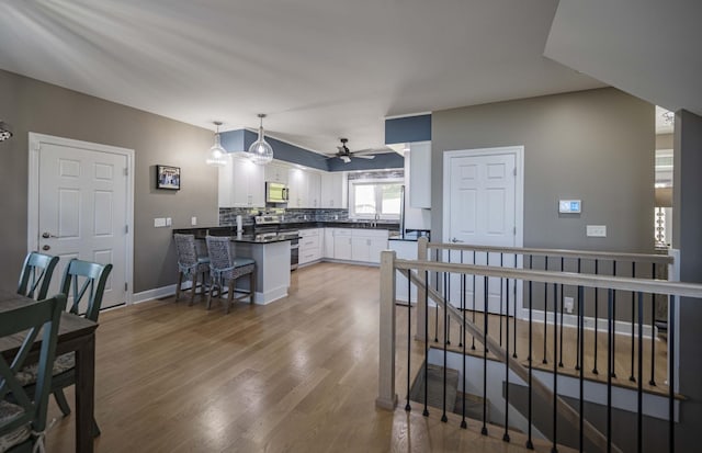 kitchen featuring ceiling fan, hanging light fixtures, backsplash, white cabinets, and appliances with stainless steel finishes