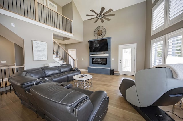 living room featuring light wood-type flooring, a towering ceiling, and ceiling fan