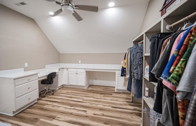 home office with lofted ceiling, ceiling fan, built in desk, and light hardwood / wood-style flooring