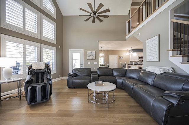 living room with hardwood / wood-style floors, ceiling fan, and a high ceiling