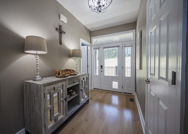 foyer entrance with light wood-type flooring and an inviting chandelier