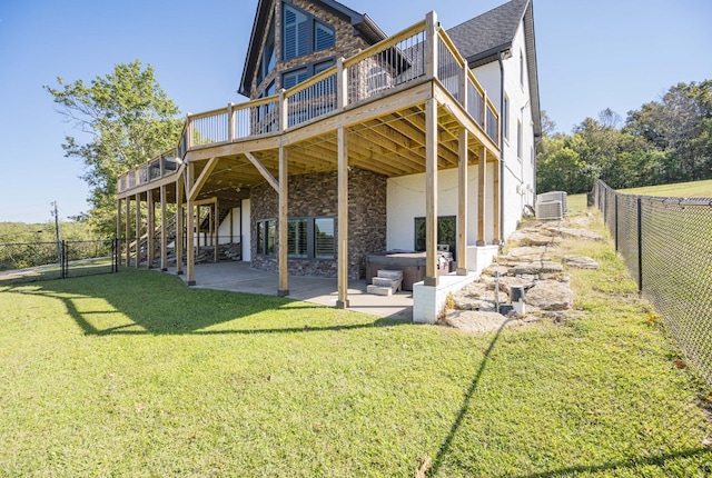 rear view of property featuring a yard, a deck, central AC, a hot tub, and a patio