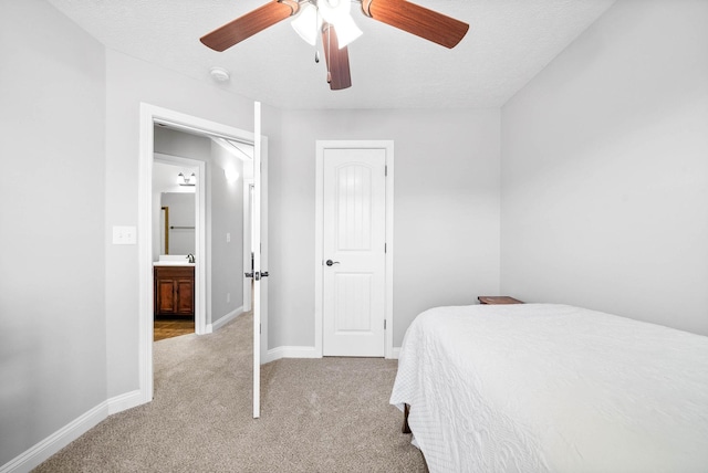 carpeted bedroom with a textured ceiling, ensuite bathroom, and ceiling fan