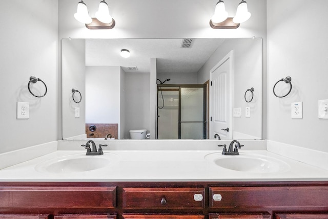 bathroom featuring a shower with door, vanity, and toilet