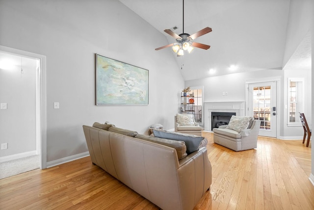 living room with ceiling fan, light hardwood / wood-style floors, and high vaulted ceiling