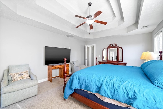 bedroom with a tray ceiling, ceiling fan, light carpet, and a textured ceiling