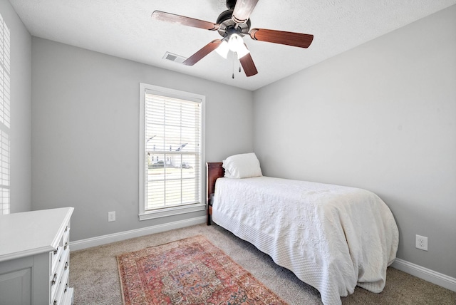 bedroom with multiple windows, ceiling fan, light carpet, and a textured ceiling