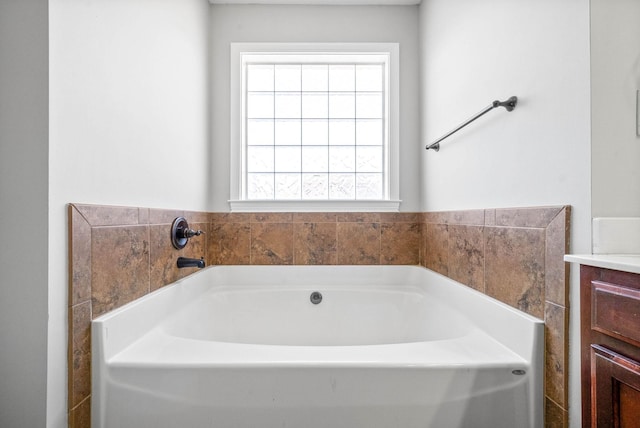 bathroom with vanity, a healthy amount of sunlight, and a tub to relax in