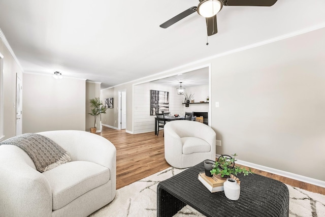 living room featuring baseboards, ceiling fan, wood finished floors, and crown molding