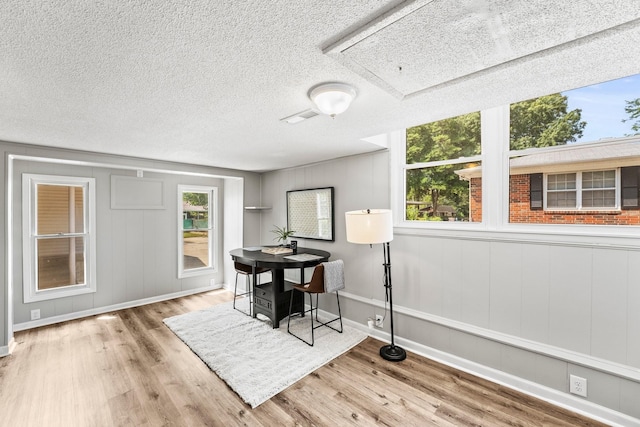 dining area with plenty of natural light, a textured ceiling, and light wood finished floors