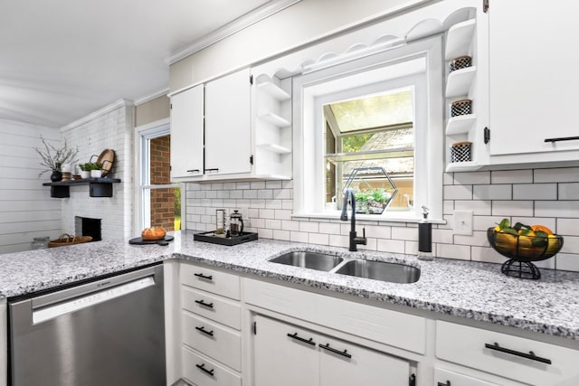 kitchen with a sink, white cabinetry, stainless steel dishwasher, light stone countertops, and open shelves