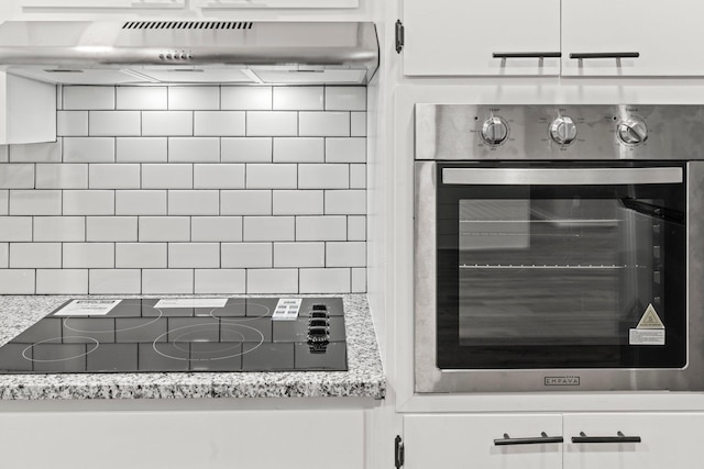 kitchen featuring black electric cooktop, under cabinet range hood, white cabinetry, stainless steel oven, and light stone countertops