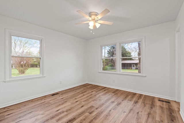 empty room with light wood-style floors, visible vents, ceiling fan, and baseboards