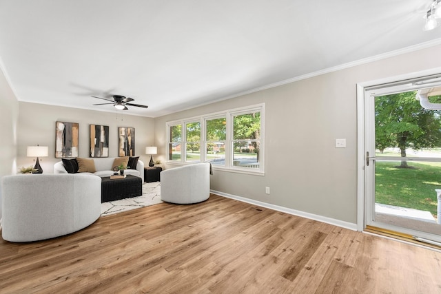 living area featuring baseboards, light wood finished floors, a ceiling fan, and crown molding