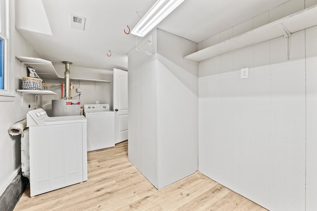 laundry area with laundry area, visible vents, light wood finished floors, and washing machine and clothes dryer