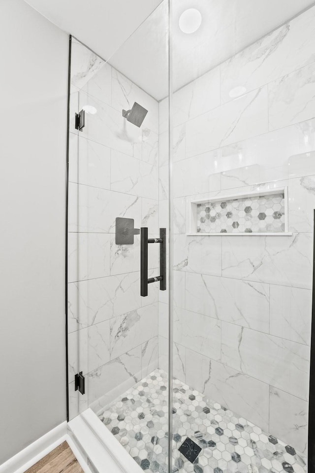 full bath featuring a stall shower, baseboards, and wood finished floors