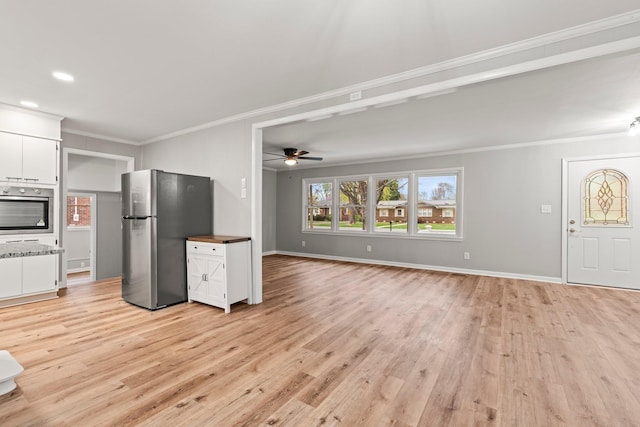 kitchen with white cabinetry, open floor plan, appliances with stainless steel finishes, light wood-type flooring, and crown molding