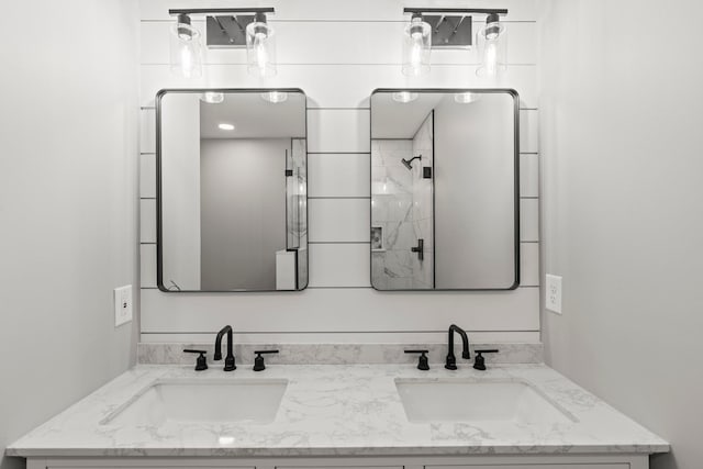 full bath featuring double vanity, a shower, and a sink