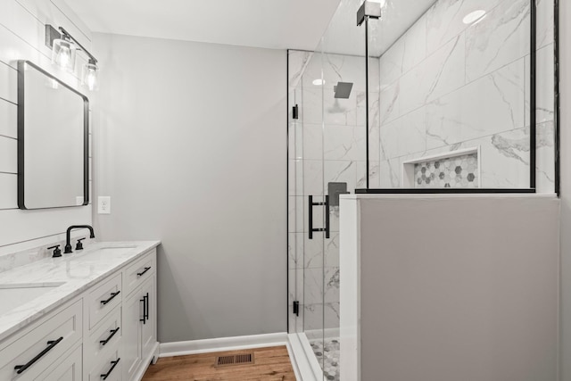 full bath with baseboards, visible vents, a sink, and a marble finish shower