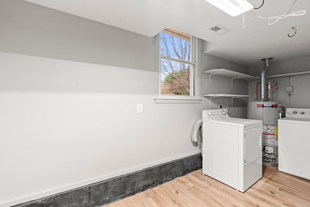 clothes washing area featuring laundry area, light wood-style flooring, water heater, and washing machine and dryer