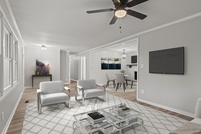 living room featuring baseboards, ceiling fan, wood finished floors, and crown molding