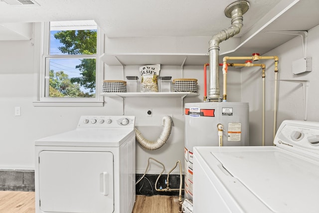 clothes washing area featuring washer and dryer, laundry area, wood finished floors, and gas water heater