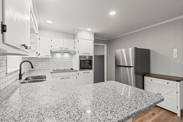 kitchen with stainless steel appliances, a peninsula, a sink, white cabinetry, and decorative backsplash