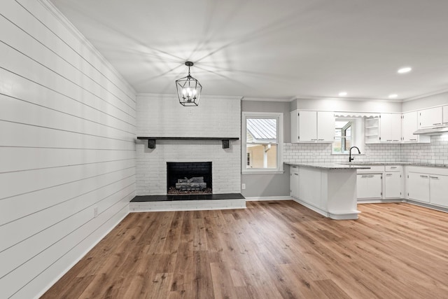 kitchen with pendant lighting, light wood finished floors, backsplash, open floor plan, and white cabinetry