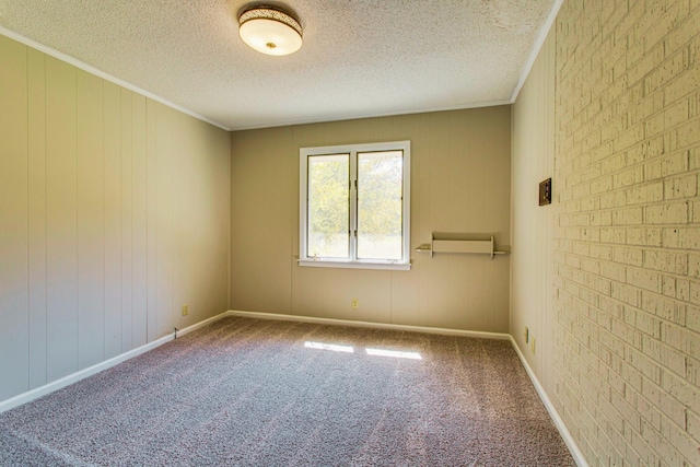 carpeted spare room with crown molding, brick wall, and a textured ceiling