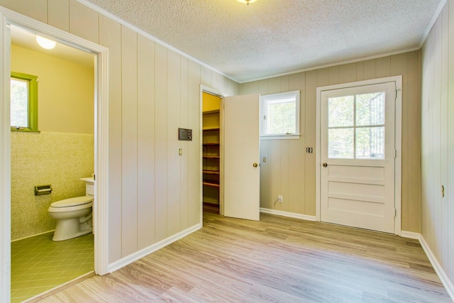 entryway with ornamental molding, a textured ceiling, and light hardwood / wood-style floors