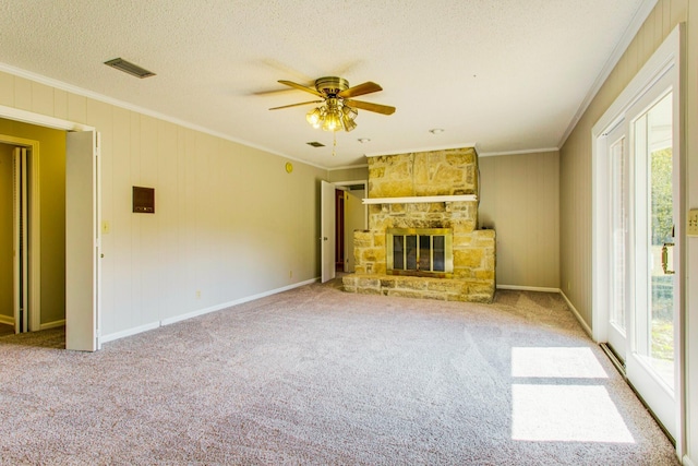 unfurnished living room with crown molding, a stone fireplace, and a wealth of natural light