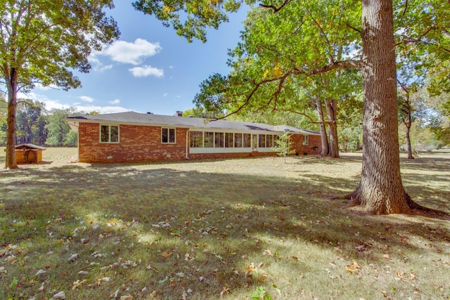 rear view of house featuring a sunroom and a lawn