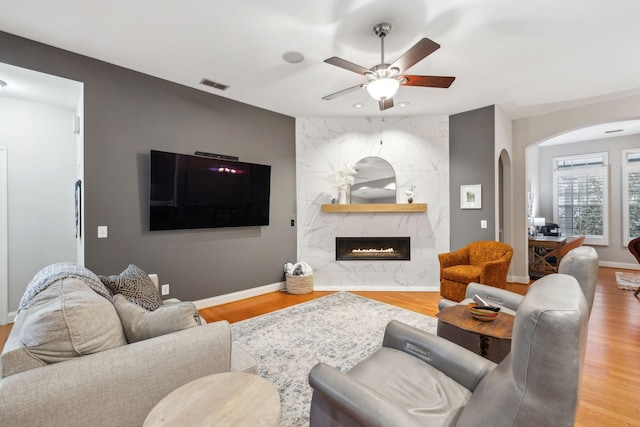 living room with hardwood / wood-style floors, ceiling fan, and a premium fireplace