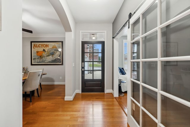 foyer with a barn door and light hardwood / wood-style flooring