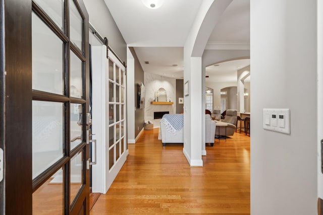 corridor featuring a barn door, light hardwood / wood-style floors, and crown molding