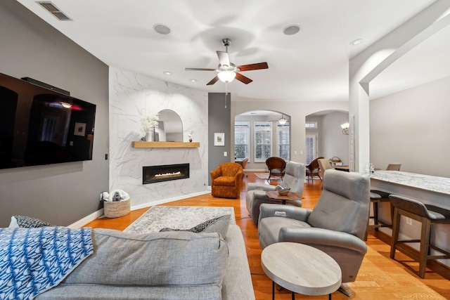 living room featuring ceiling fan, light hardwood / wood-style floors, and a premium fireplace