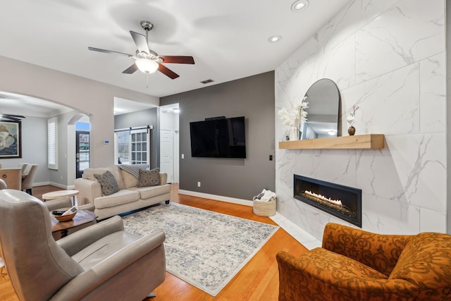 living room featuring ceiling fan, a fireplace, and light hardwood / wood-style flooring