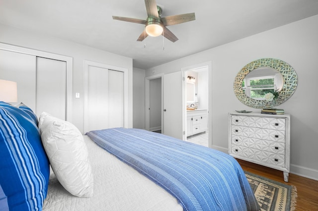 bedroom featuring ensuite bathroom, ceiling fan, sink, wood-type flooring, and multiple closets